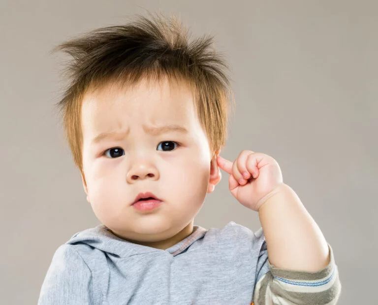 Enfant qui touche son oreille avec un doigt